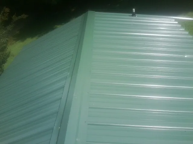 New green metal panels meeting at the ridge of a roof — Flat Roof Repair work by our crew in Deer Park
