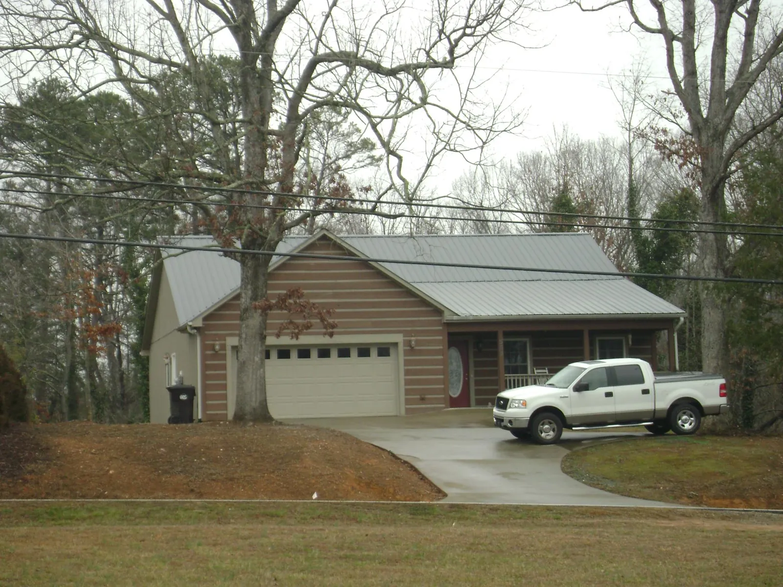 Gray metal roof on a log sided house with an attached two car garage in Deer Park